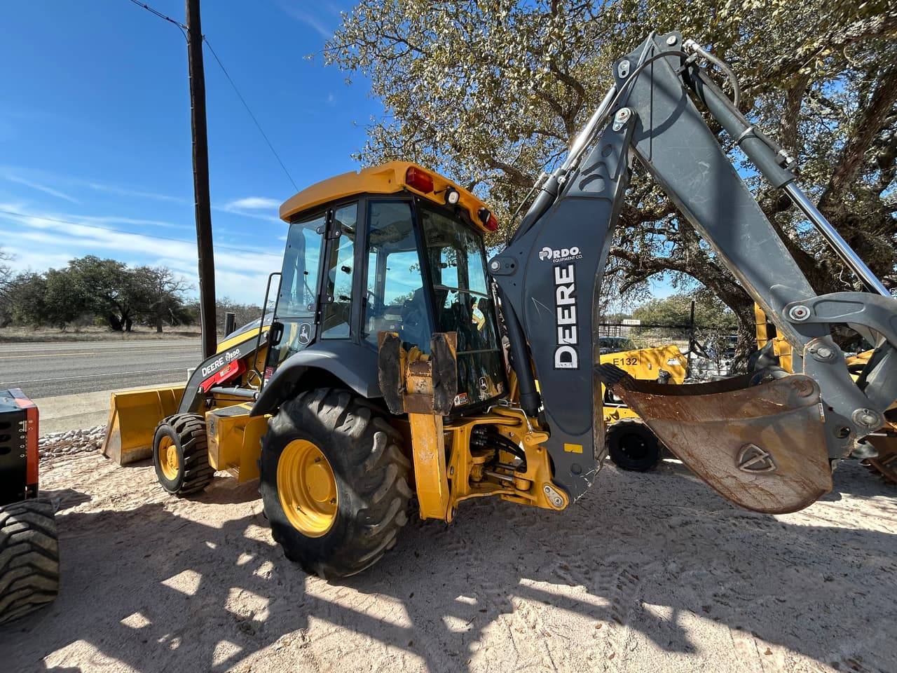 John Deere backhoe loader with front bucket and extended backhoe arm in Buchanan Dam, TX