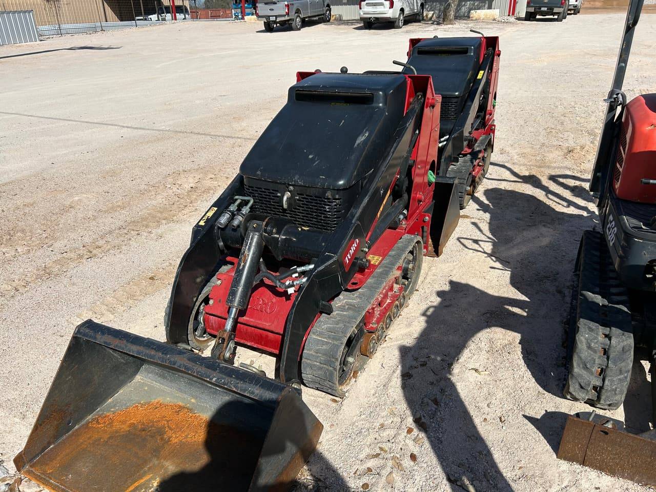 Red Toro Dingo stand-on mini track loader with bucket on the 4-T Rental & Sales yard